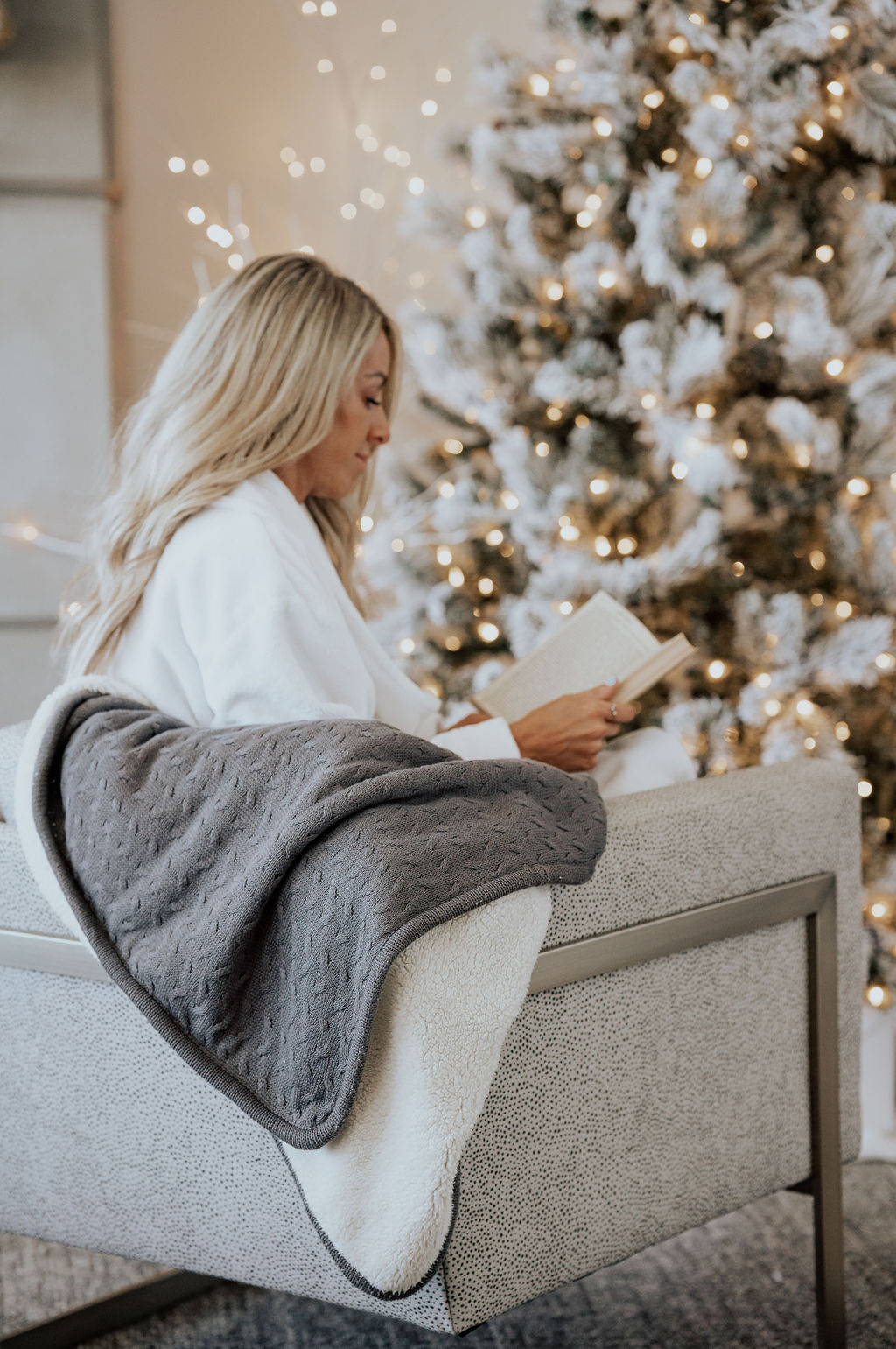 model wearing cariloha robe while reading a book next to a christmas tree